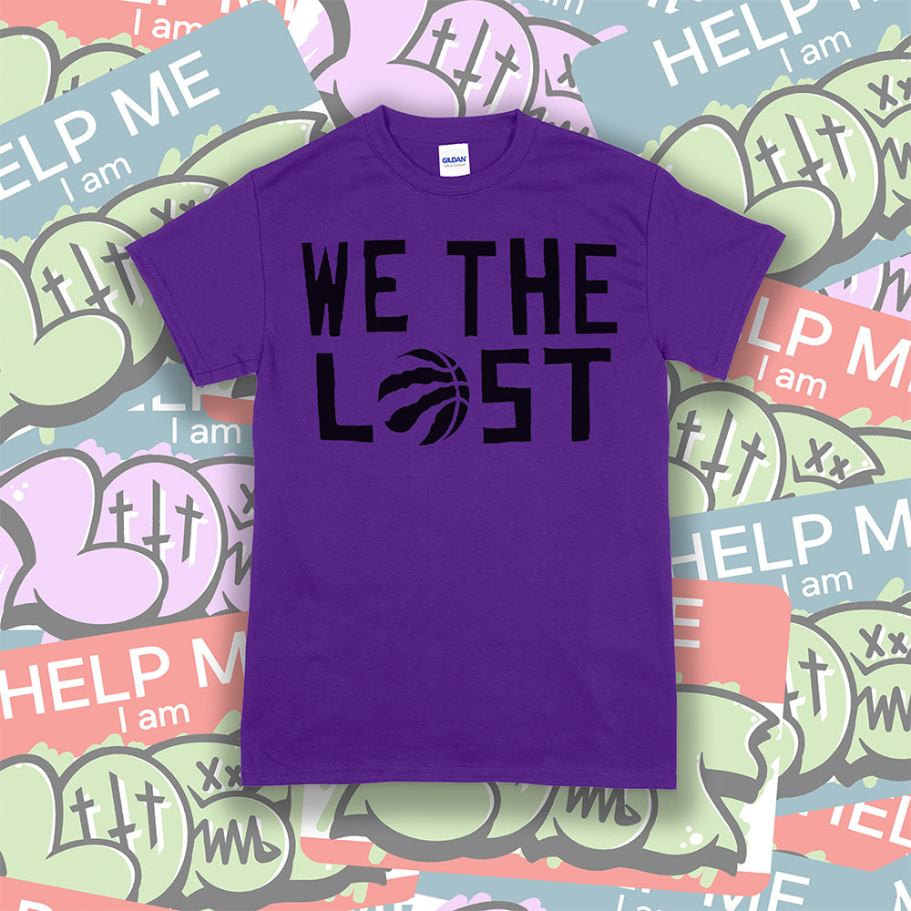 We The Lost t-shirt. Bold black lettering screen printed on a purple shirt. Assorted colorful graffiti stickers make up the background.