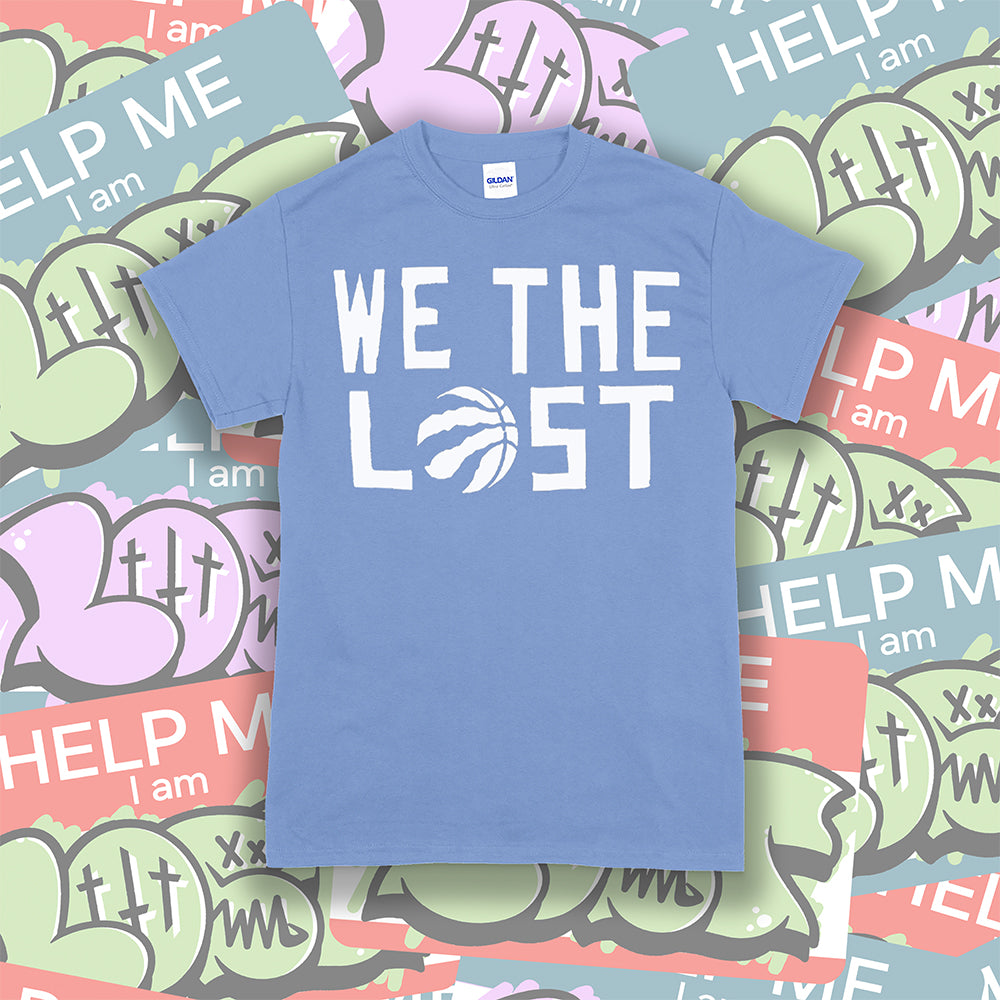 The We The Lost t-shirt. Bold white lettering and raptor claw design screen printed onto a light blue colored shirt. A collection of brightly colored graffiti stickers makes up the background.